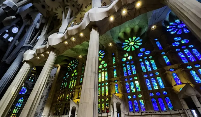 Interior view of the Sagrada Familia in Barcelona, showcasing its intricate columns and colorful stained glass windows.