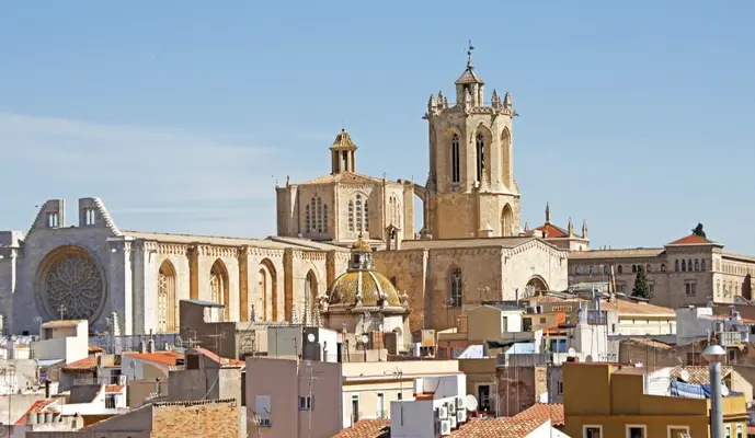A majestic cathedral towers over the city skyline, showcasing intricate architecture against a clear blue sky.