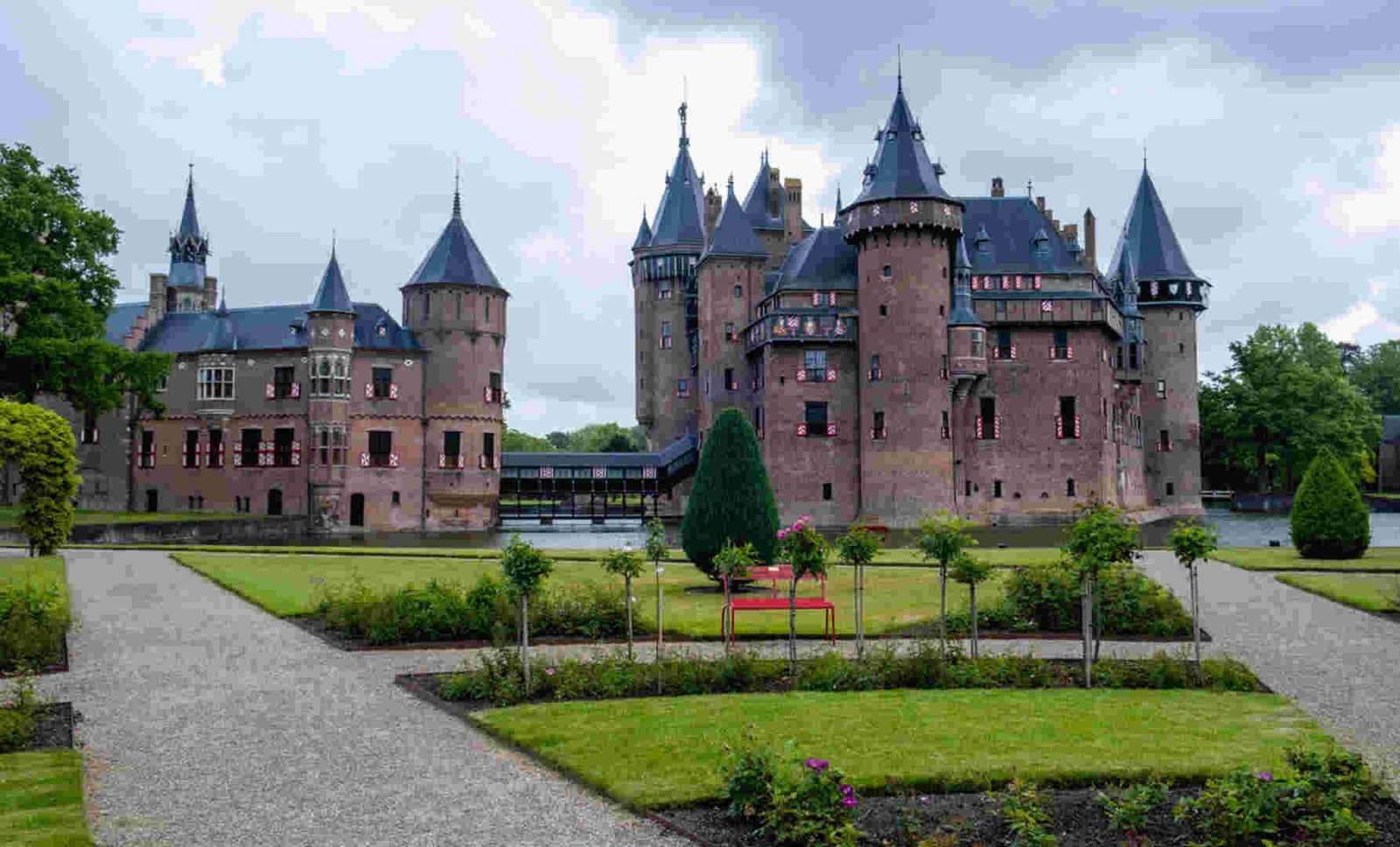 A beautiful medieval castle surrounded by lush gardens and a serene water body.