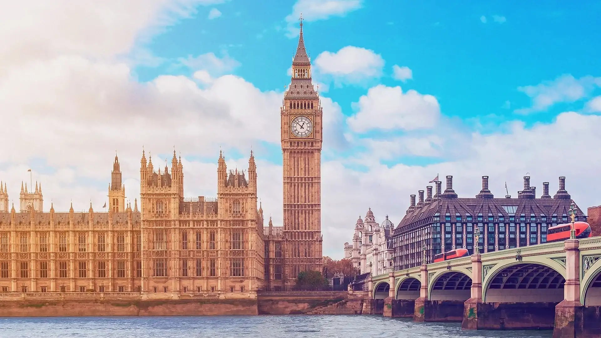 The iconic Big Ben and the Houses of Parliament beside the River Thames, with blue skies and clouds in the background