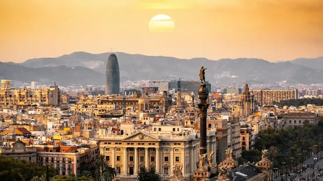 A panoramic view of Barcelona at sunset, showcasing vibrant colors illuminating the skyline and iconic architecture.
