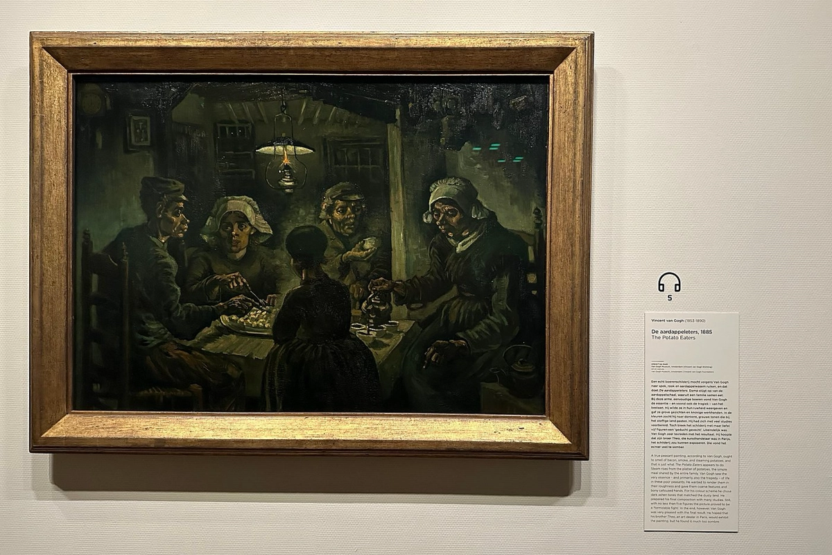 The Potato Eaters" by Van Gogh, displayed framed on a museum wall beside its descriptive plaque.