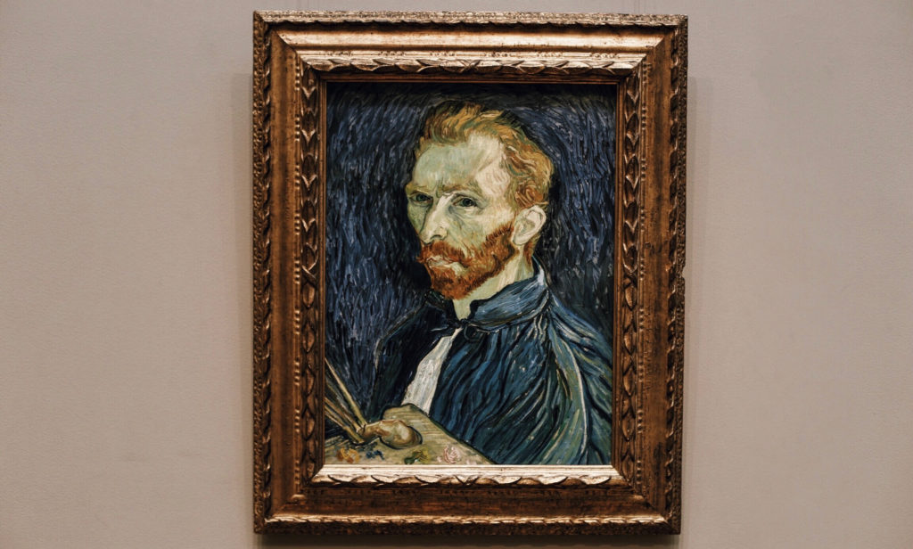 A framed painting of a man with reddish hair and beard, wearing a blue coat, holding a palette and brushes, set against a textured background. The art style features bold brushstrokes and vivid colors.