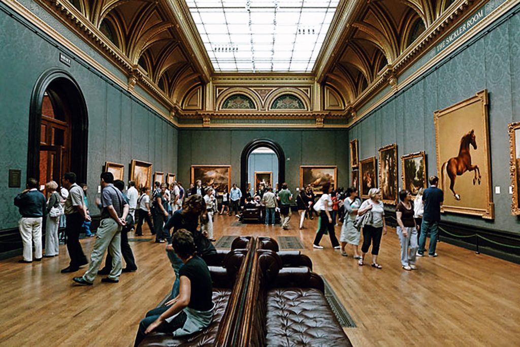 A bustling art gallery with several people admiring paintings on the walls. The room has a high ceiling, ornate decor, and cushioned seating in the center. Paintings of various sizes are displayed, including a prominent image of a horse.