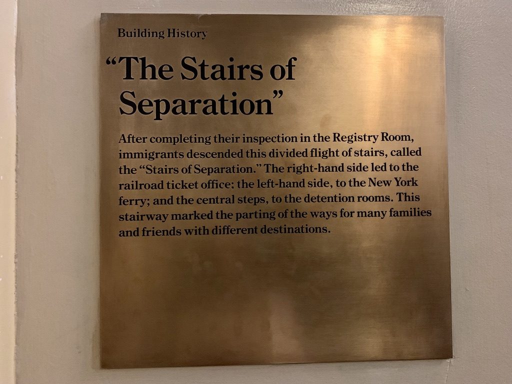 Plaque titled The Stairs of Separation explaining how immigrants, after inspection, used different stairs for destinations: railroad office, New York ferry, or detention rooms. Significance lies in the emotional partings of families and friends.